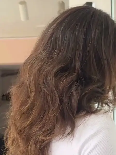 Antes: cabello castaño, ondulado y con volumen, visto de espaldas